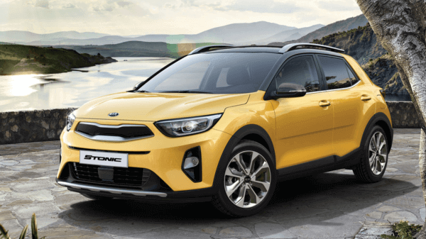 A yellow color Kia Stonic SUV parked next to a mountain