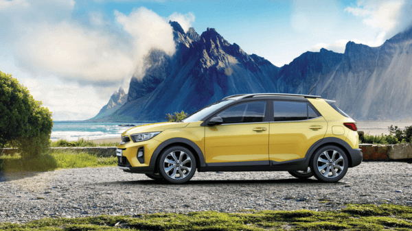 A yellow color Kia Stonic SUV parked in a beach location