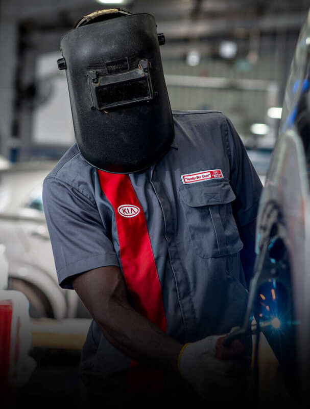 A motor mechanic with safety equipments is repairing at Kia collision repair
