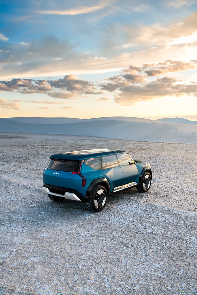 A New blue color Kia SUV with a sunset in a mountain area