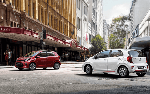 Red color and white color Kia picanto hatchbacks in a city